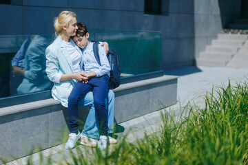 Loving Mom Comforts Her Tired Son After School on a Bench Outside