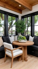 Obraz premium This cozy corner nook showcases light wood seating, a round table, and large windows bringing in natural light, accented by plants