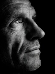 Obraz premium Close-up portrait of a pensive mature man in dramatic black and white lighting
