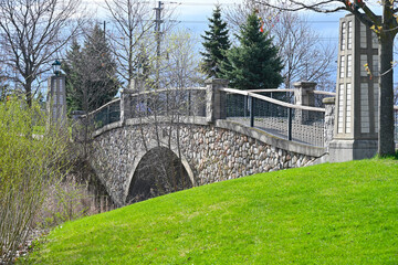 Stone bridge over the stream in a public park in springtime