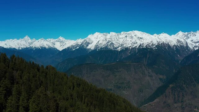 Scenic drone view of Makra Mountain in Siri Payee, with dense plants and snow covered mountains