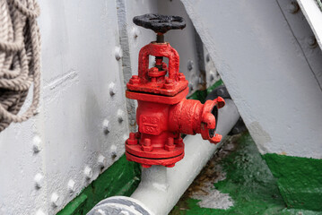 An old red fire hydrant on board a ship.