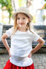 blonde girl in a hat and red skirt posing in the park