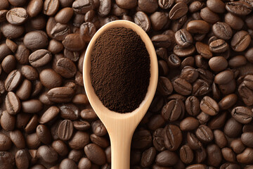 Obraz premium A wooden spoon filled with dark roasted coffee grounds rests on a bed of roasted coffee beans. The image is rich in color and texture.
