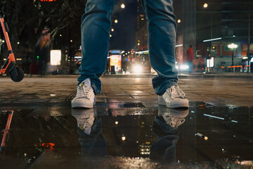 A man standing at a puddle during night
