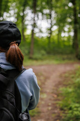 girl travels through the forest with a backpack. close-up from the back