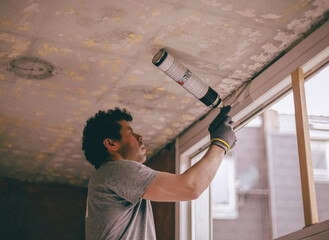 A worker fills cracks with polyurethane foam.