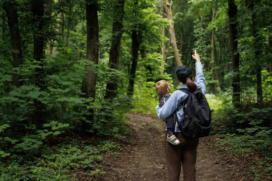 girl travels through the forest with a child and a backpack.family travel.family concept - Powered by Adobe