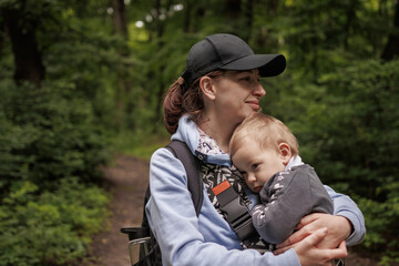 Mother holding baby looking up in forest. Nature walk with baby, peaceful moment outdoors, family bonding in forest.