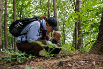 woman showing her child nature and fauna during walk in forest. Nature walk with baby, peaceful moment in fresh air, family bonding in forest.