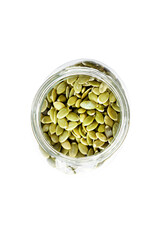 Top view of a glass jar full of shelled pumpkin seeds.