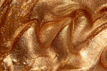 Glowing golden shimmering cosmetic texture of gel or body spray. Background texture for backdrops or mapping.