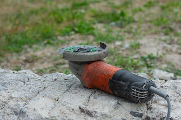 Close-up of an angle grinder with a green segmented diamond cutting disc placed on rough concrete...