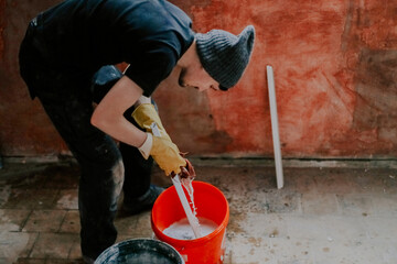 A man washes the plastic part of a frame with a sponge in a bucket.