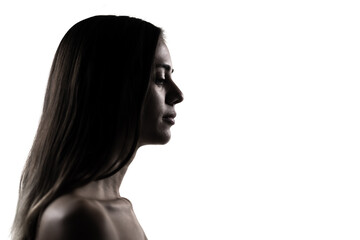 Elegant silhouette of a young woman in a studio setting, profile portrait with a serene expression © Nikola Spasenoski