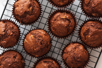 Freshly baked chocolate muffins on a cooling rack. Soft focus