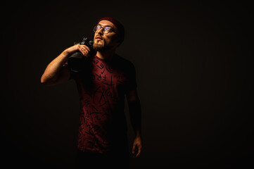 Moody portrait of a stylish photographer in beanie and glasses holding a camera on shoulder....