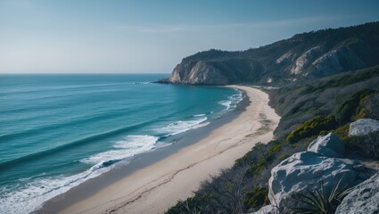 Fototapeta premium A beautiful view of a beach and ocean with a rocky hill in the background. The sky is clear and the water is calm.