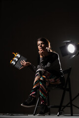 Naklejka premium Female movie director on set with smoke background. Girl holding clapperboard on fire.