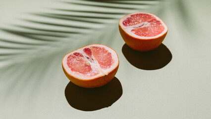 Fresh healthy grapefruit slices on green background with palm leaf shadow. Creative minimal...