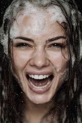 Joyful woman with wet hair laughing amidst a playful bubble bath, capturing a moment of happiness and spontaneity in an intimate setting