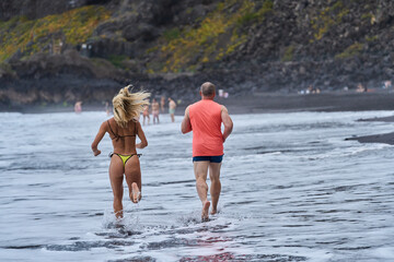 Couple jogging on volcanic beach