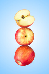 Apples stacked on top of each other against light blue background. Balance