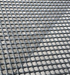 View of pavement through geometric metal grid