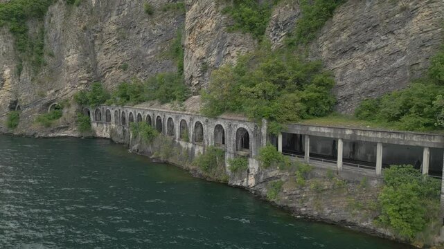 Mountain road tunnels along Lake Como between Olcio and Lierna, Italy, with lush cliffs and scenic alpine backdrop on a summer day