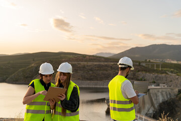 Engineers using digital tablet and laptop at dam construction site