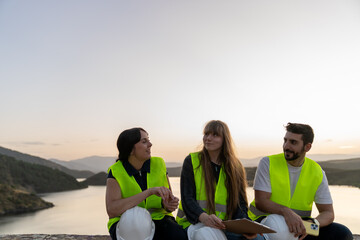 Engineers discussing project details at sunset by the lake