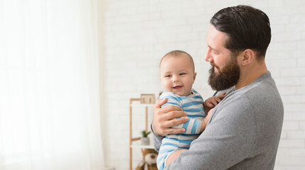 Paternal pride. Happy millennial man holding his baby son, panorama with empty space © Prostock-studio