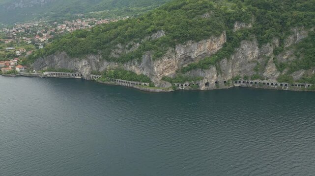 Mountain road tunnels along Lake Como between Olcio and Lierna, Italy, with lush cliffs and scenic alpine backdrop on a summer day