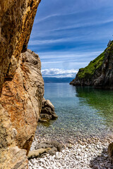 The crystal clear blue water of the Adriatic Sea, a hidden entrance to a small beach that is a...