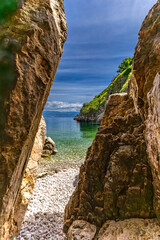 The crystal clear blue water of the Adriatic Sea, a hidden entrance to a small beach that is a...