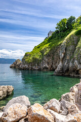 The crystal clear blue water of the Adriatic Sea, a hidden entrance to a small beach that is a...