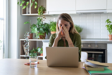 Upset overwhelmed woman with head in hands work on laptop exhausted from work study with burnout and stress. Eye fatigue, remote job overload, mental exhaustion, emotional distress, anxiety issues