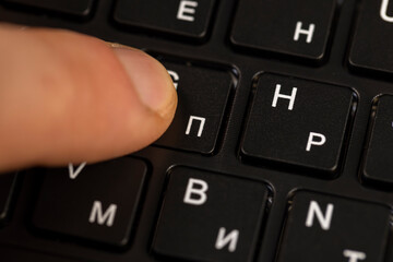 black computer keyboard with English and Russian letters close up, the black keyboard in the layout of letters in several languages