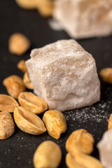 scattered oriental sweets Turkish delight with peanuts on a black slate board, close up