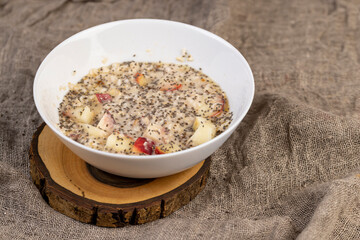 adding chia seeds to hot oatmeal with fruits, quickly cooked oatmeal porridge with fruits and berries and lots of chia seeds, close up