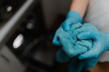 Cleaning service employee wearing gloves holding towel after cleaning modern kitchen oven, ensuring...