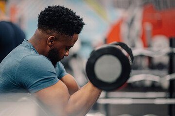 Determined bodybuilder lifting dumbbell, concentrating on biceps exercise in gym