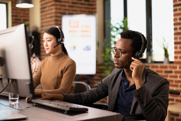 Black male entrepreneur wearing a headset, attentively listening during an online marketing...