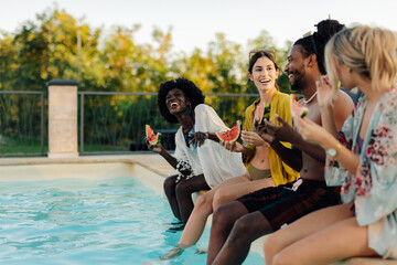 Happy friends eating watermelon by the pool during summer holidays