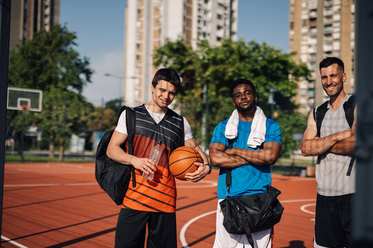 Three basketball players posing on outdoor court after training