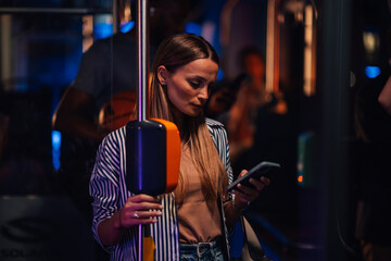 Young woman using smartphone on a night bus ride