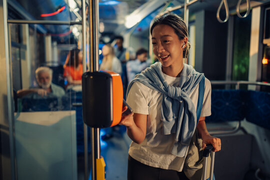 Young woman paying bus fare with contactless payment on public transport