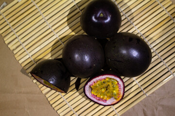 Fresh Passion Fruits and a Halved Fruit Displayed on a Bamboo Mat