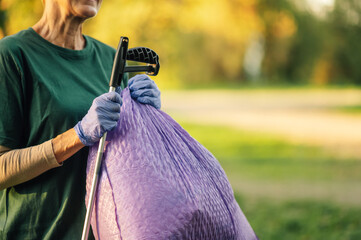 Senior volunteer picking up trash in public park