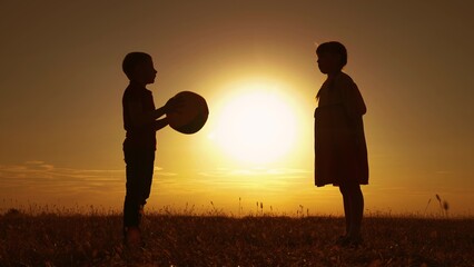 Children play with big ball in park, sun. Family weekend. Happy child throws ball with his hands. Kids, boy, girl have fun with ball in park, sunset. Sports games for children outdoor. Family holiday